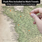 The image is a detailed map of France, with various locations marked and labeled. A hand is holding a pin, suggesting that the map is interactive and allows users to pin specific locations. The map is printed on a canvas, indicating that it is a printed representation rather than a digital image. The image is a collage of multiple images, and the caption provided is a brief description of the image without any redundancy or vague wording.