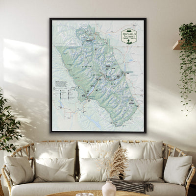 a large framed map of the mountainous region of Montana, with various locations and landmarks marked on it. The map is displayed on a wall above a couch, creating a cozy and inviting atmosphere in the living room.