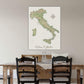 a large map of Italy hanging on a wall above a wooden dining table with four chairs.