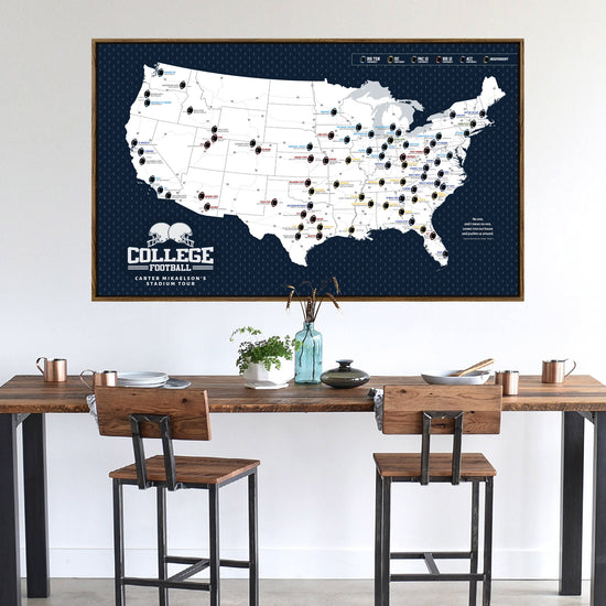 a large map of the United States with various locations marked, displayed on a wall above a wooden dining table with two chairs.
