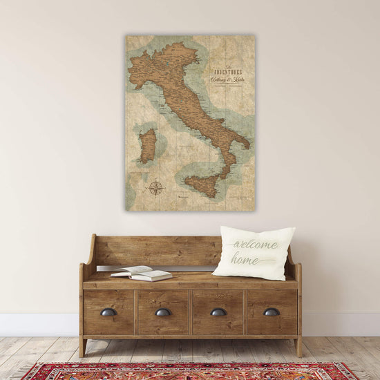 a wooden bench with a "welcome home" pillow on it, and a large map of Italy hanging on the wall above it.