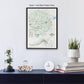 a framed map of Yosemite National Park hanging on a wall, with a glass dome containing a plant, a white clock, and a stack of books below it.