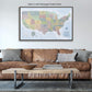 a large framed map of the United States hanging on a wall above a brown leather couch in a living room setting.