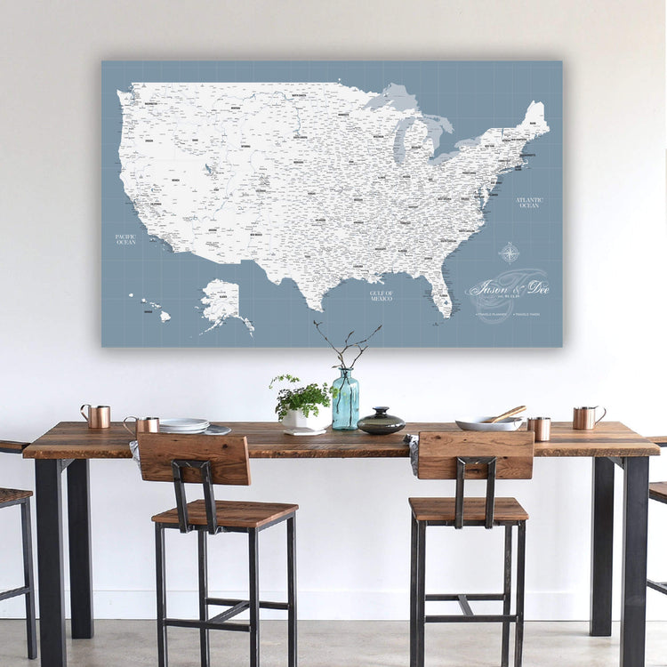 a large map of the United States displayed on a wall above a wooden dining table with chairs.